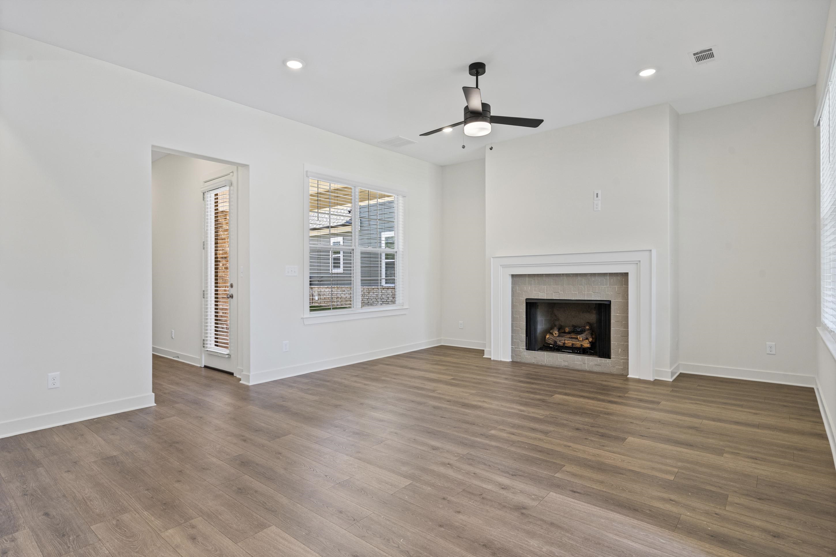 5702 Gerber Road Arlington, TN 38002 - Photo 5 of 27 Spacious living area featuring wood-finish flooring, a contemporary ceiling fan, recessed lighting, a fireplace with a stone surround and white mantel, and a glass-paneled exterior door
