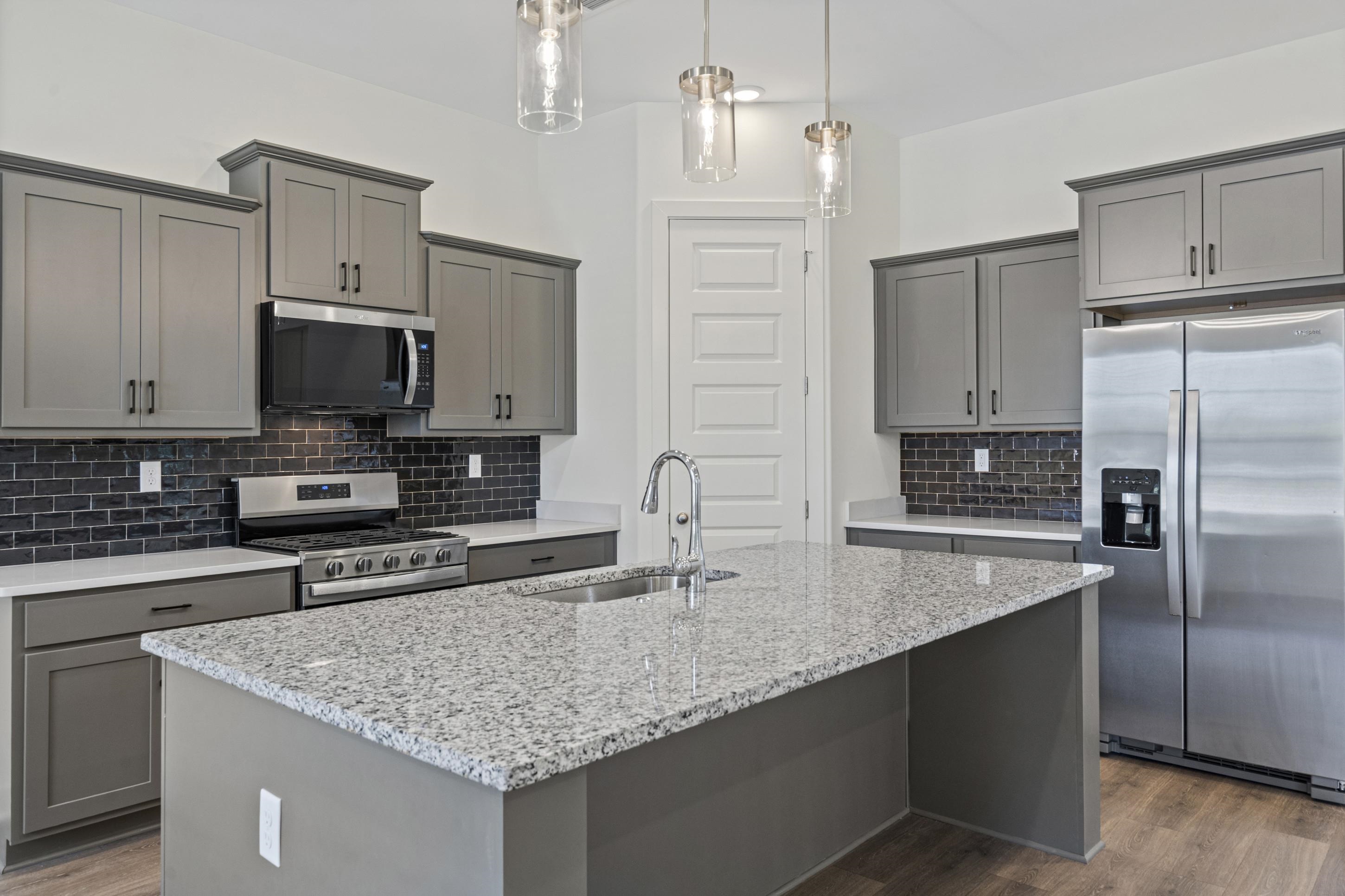 5702 Gerber Road Arlington, TN 38002 - Photo 7 of 27 Kitchen featuring grey cabinetry, stainless steel appliances, a dark subway tile backsplash, light stone countertops, and wood-finish flooring