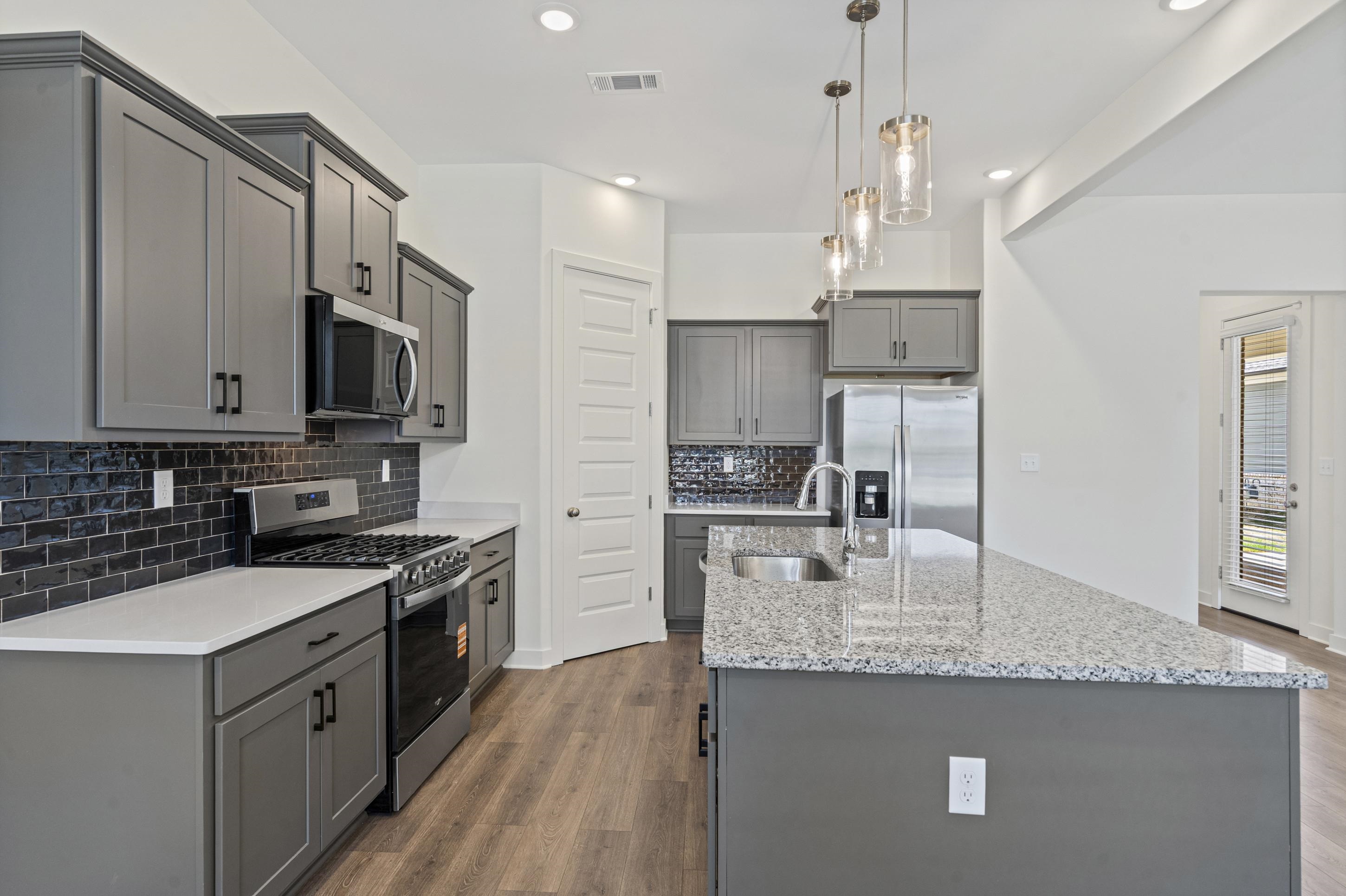 5702 Gerber Road Arlington, TN 38002 - Photo 8 of 27 Kitchen featuring wood-finish flooring, gray cabinetry with dark hardware, white countertops, and a dark subway tile backsplash