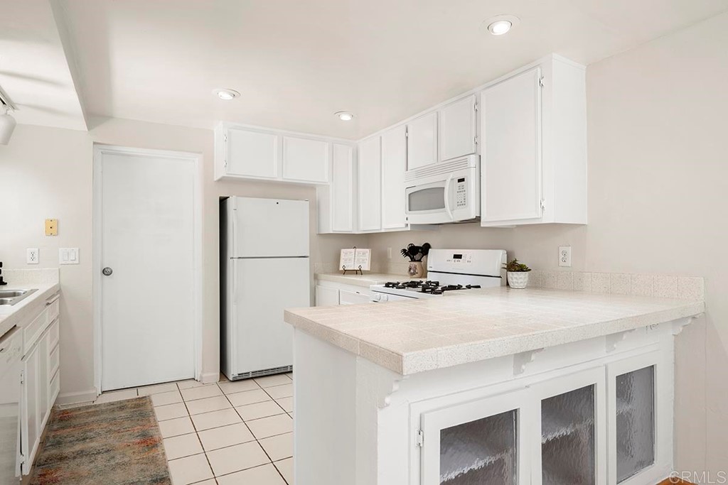 10281 Alphonse Street Santee, CA 92071 - Photo 11 of 26 a kitchen with a sink a refrigerator a stove and white cabinets