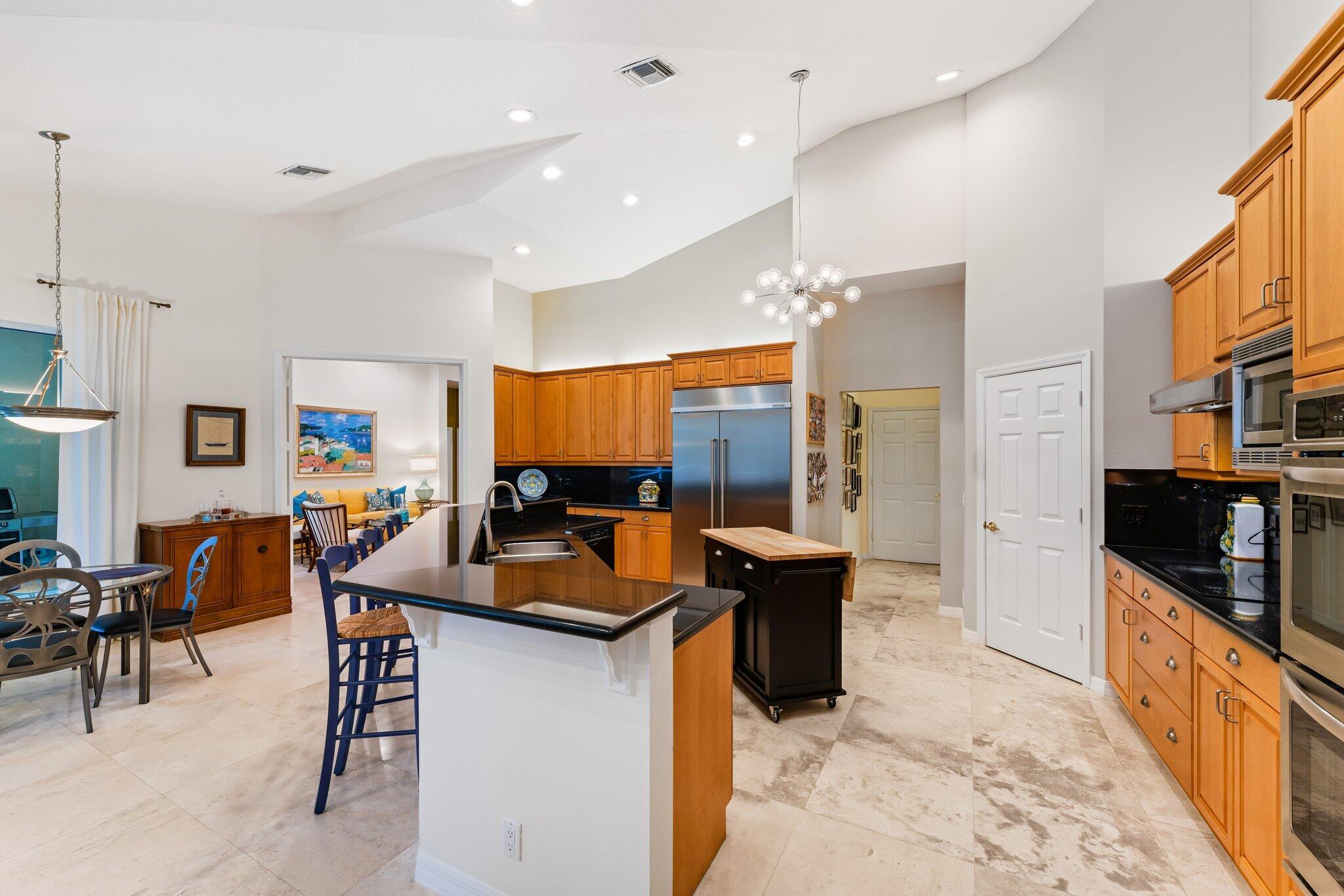 248 River Drive Tequesta, FL 33469 - Photo 56 of 65 a kitchen with stainless steel appliances granite countertop a stove top oven a sink a dining table and chairs