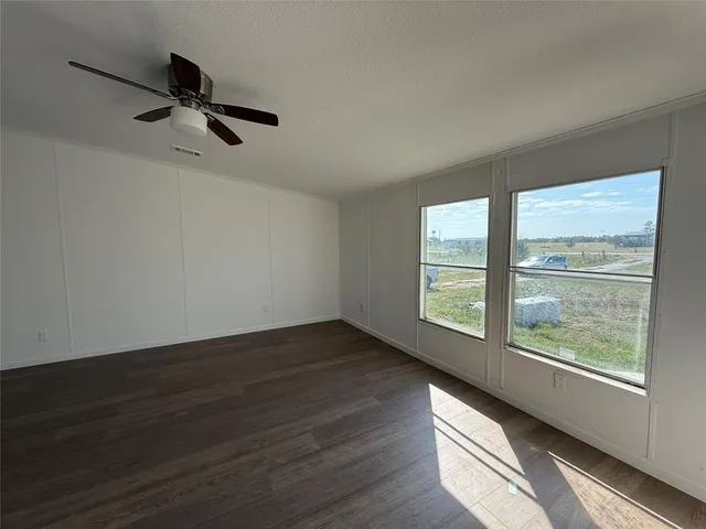a view of empty room with wooden floor and fan