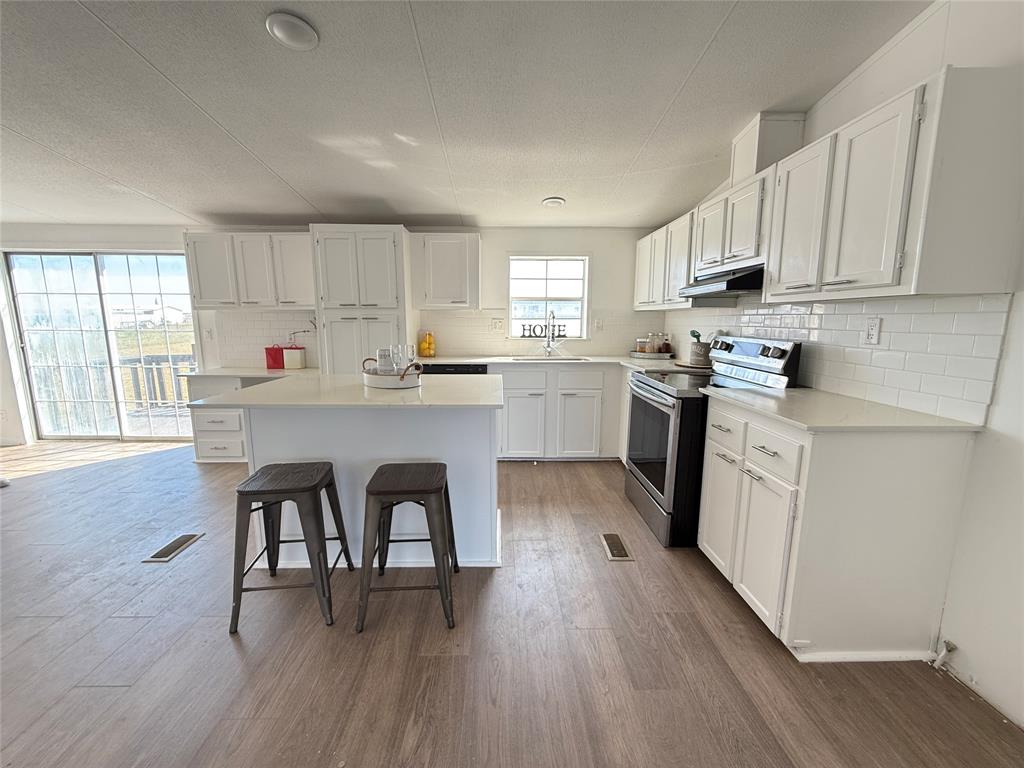 835 Private Road 4732 Rhome, TX 76078 - Photo 6 of 30 a kitchen with a stove a sink and white cabinets with wooden floors