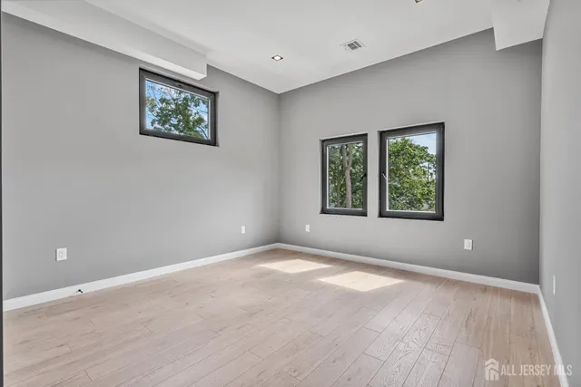 a view of an empty room with window and wooden floor
