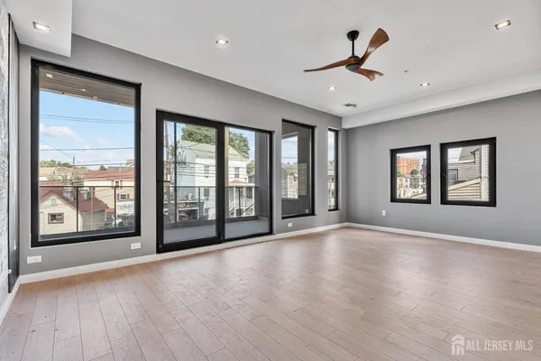 a view of an empty room with a window and wooden floor