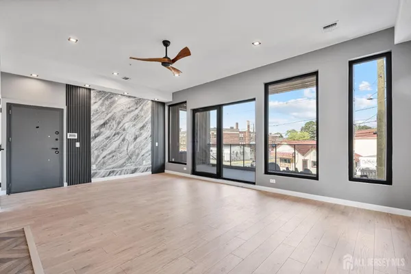a view of an empty room with a window and wooden floor