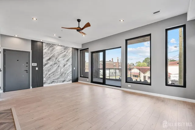 a view of an empty room with a window and wooden floor