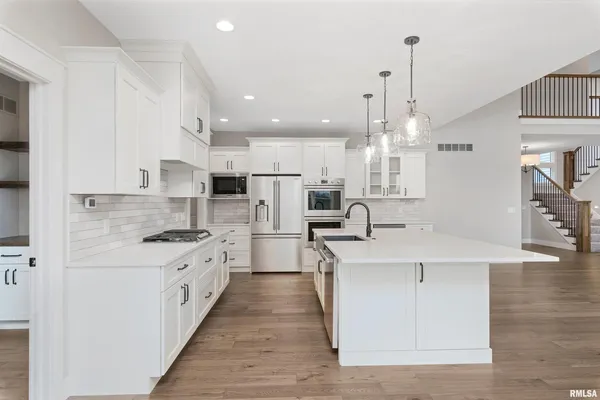 a large kitchen with stainless steel appliances kitchen island granite countertop a sink a stove and a refrigerator