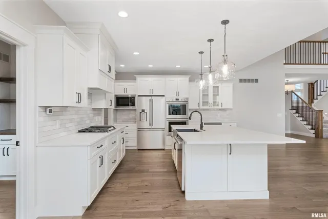 a large kitchen with stainless steel appliances kitchen island granite countertop a sink a stove and a refrigerator