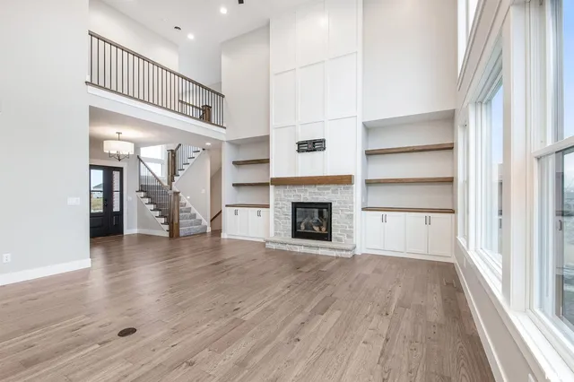 a view of an empty room with wooden floor fireplace and a window