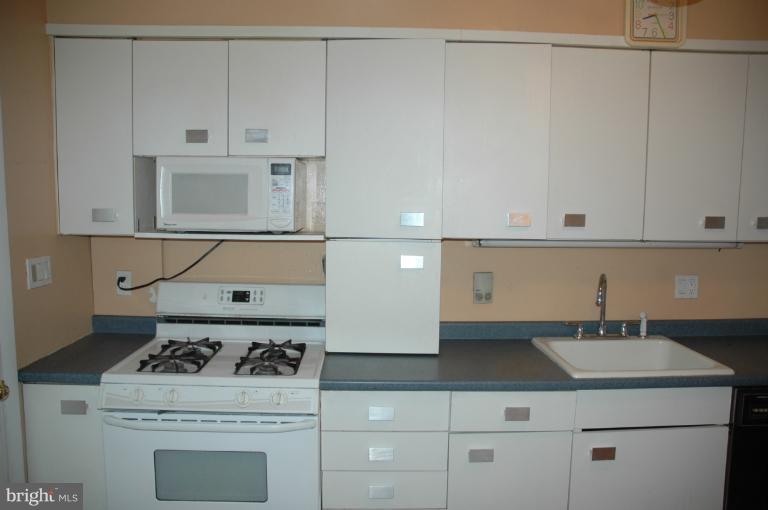 4170 Crest Heights Road Baltimore, MD 21215 - Photo 22 of 30 a kitchen with a stove and white cabinets