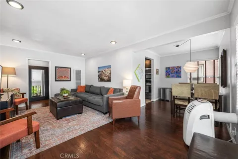 a living room with furniture kitchen view and a wooden floor