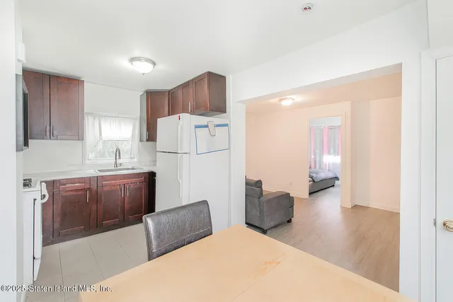 a large white kitchen with a refrigerator a stove top oven and a sink