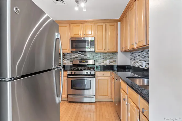a kitchen with stainless steel appliances granite countertop a refrigerator a sink and a stove