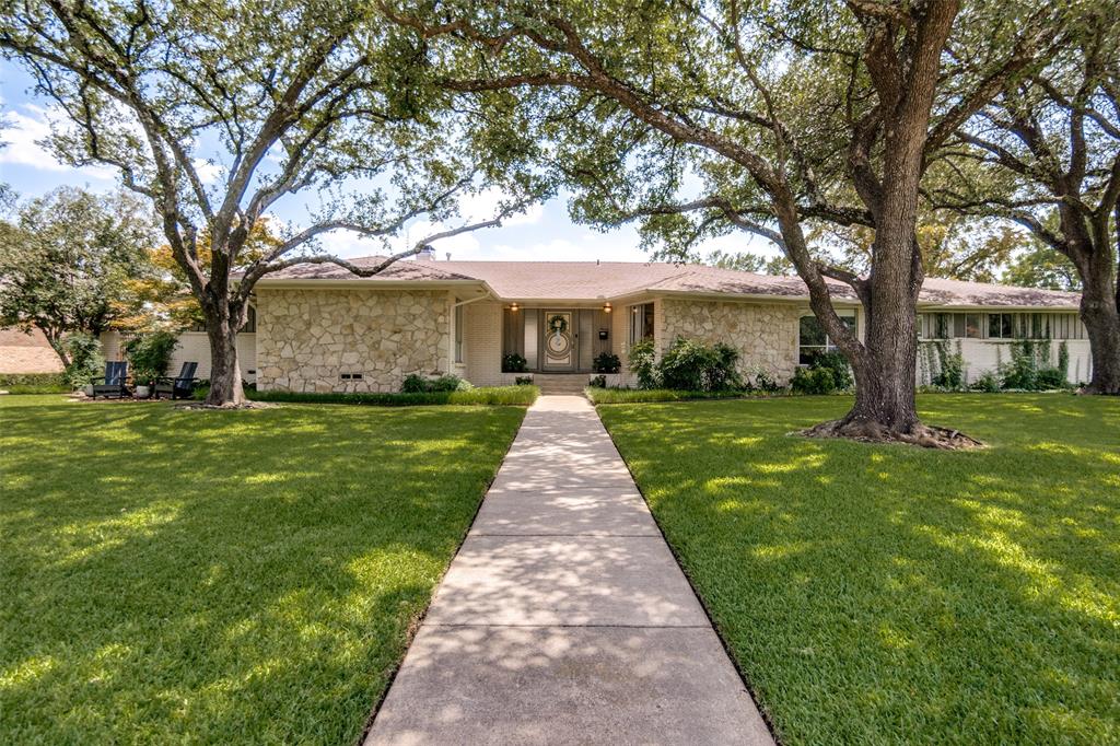 Stone facade exterior with a concrete walkway and mature trees
