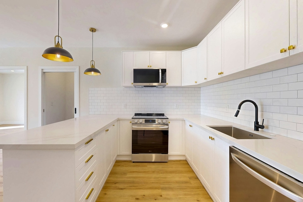 476 Warren Street Boston, MA 02121 - Photo 13 of 29 a kitchen with stainless steel appliances granite countertop a sink a stove and a wooden floors