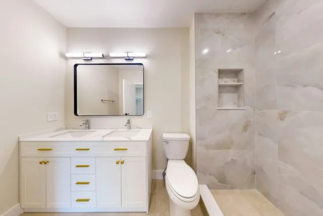 a bathroom with a granite countertop toilet sink and mirror