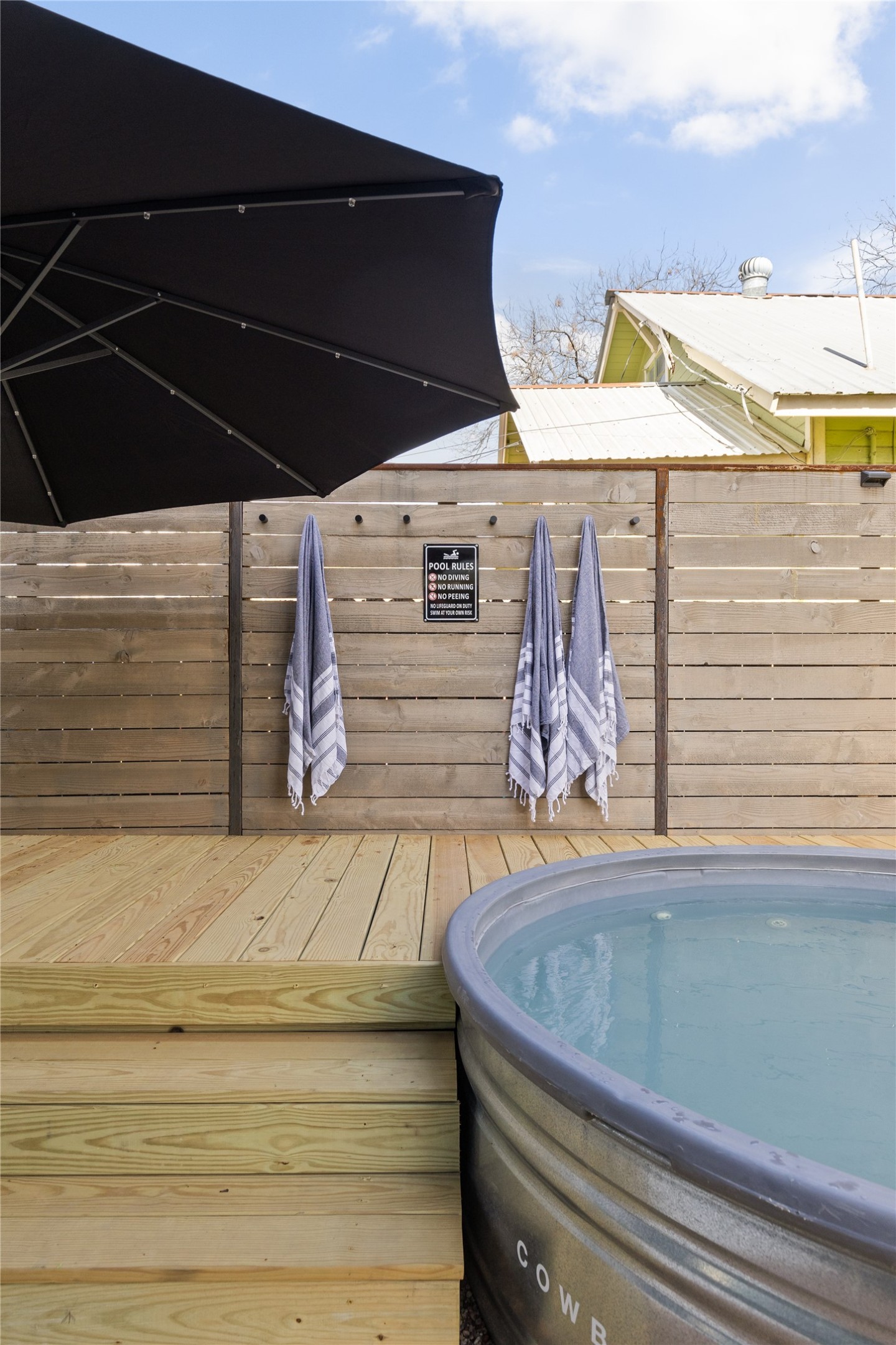 106 Comal Street Austin, TX 78702 - Photo 13 of 40 A private outdoor retreat features a stock tank spa beside a slatted privacy fence.