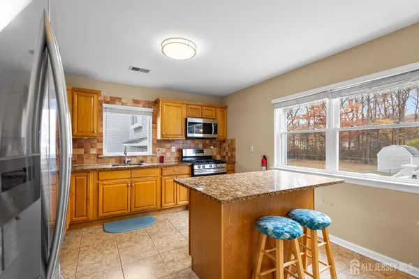 a kitchen with stainless steel appliances granite countertop wooden cabinets a stove a sink and a refrigerator