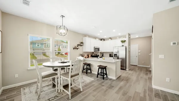 a kitchen with stainless steel appliances kitchen island granite countertop a dining table chairs and white cabinets