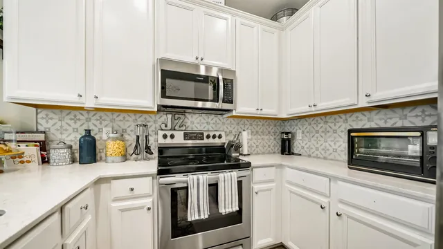 a kitchen with white cabinets and appliances