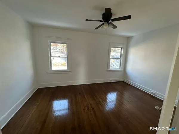 a view of an empty room with wooden floor and a window