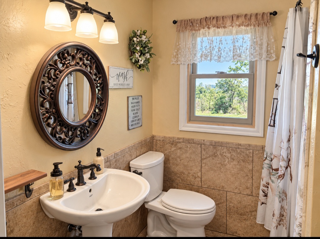12526 3520th Road Seminole, OK 74868 - Photo 22 of 42 Pedestal sink with dark bronze faucet, decorative round mirror, and a three-light vanity fixture
