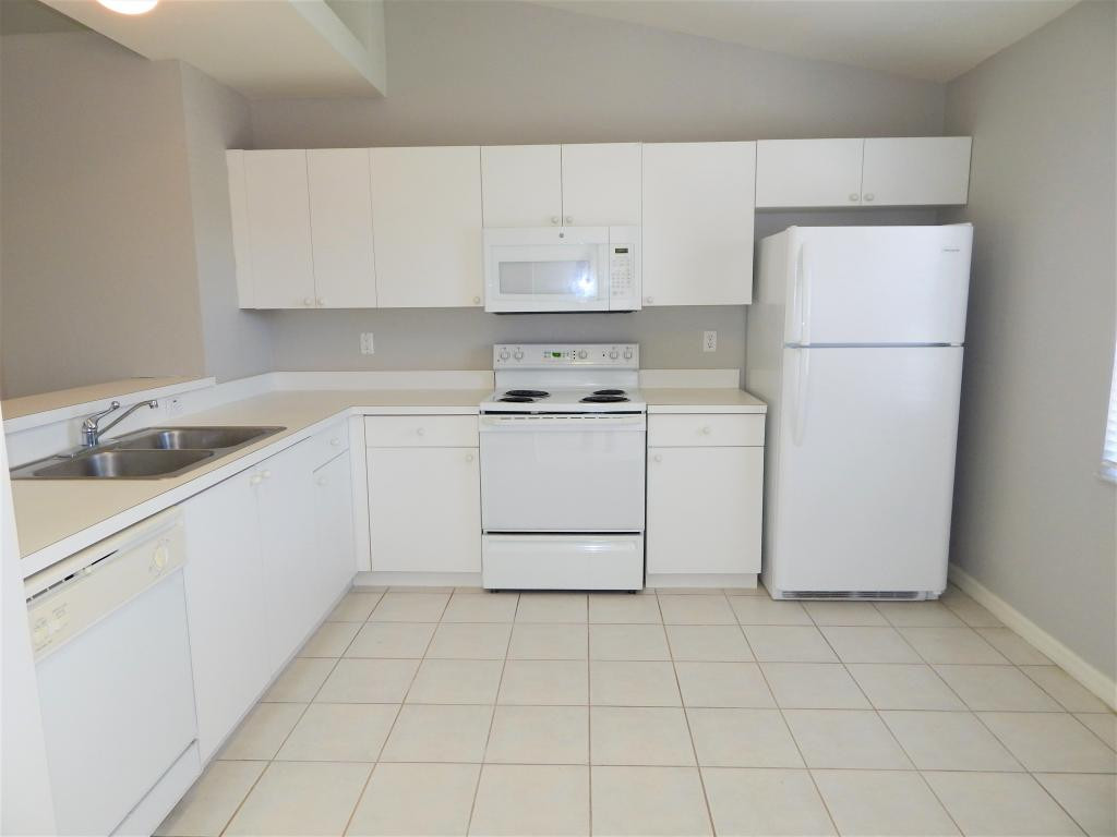 8065 Tiger Cove, Unit 1610 Naples, FL 34113 - Photo 4 of 11 a kitchen with cabinets and white appliances