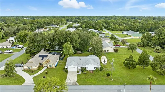 an aerial view of residential houses with outdoor space and trees