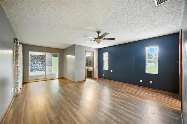 a view of an empty room with window and wooden floor