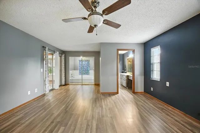 a view of empty room with wooden floor and fan