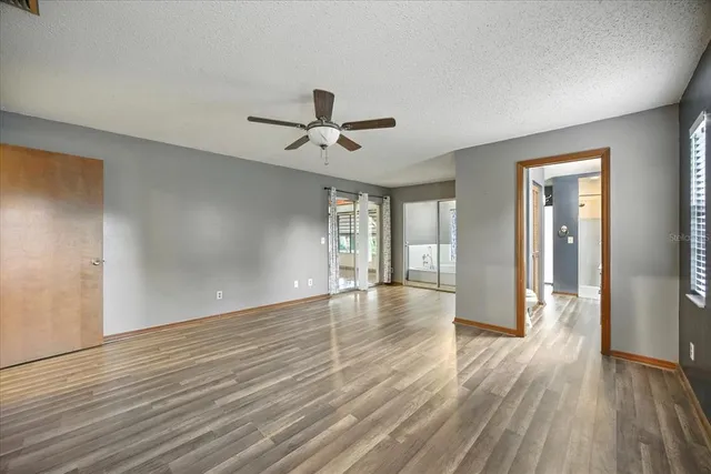 a view of empty room with wooden floor and fan