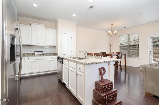 a kitchen with kitchen island granite countertop wooden floors and white cabinets