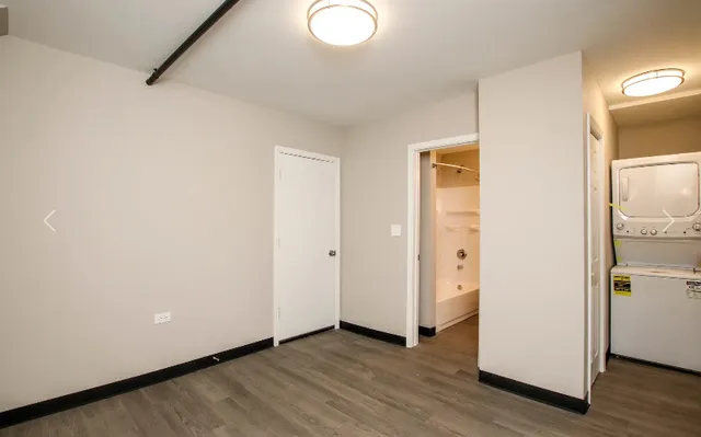 a view of an empty room with wooden floor and a bathroom
