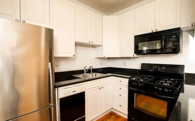 a kitchen with stainless steel appliances granite countertop white cabinets a stove a microwave and a refrigerator