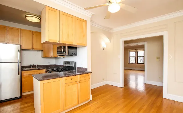 a kitchen with granite countertop a refrigerator a stove top oven a sink and dishwasher with wooden floor