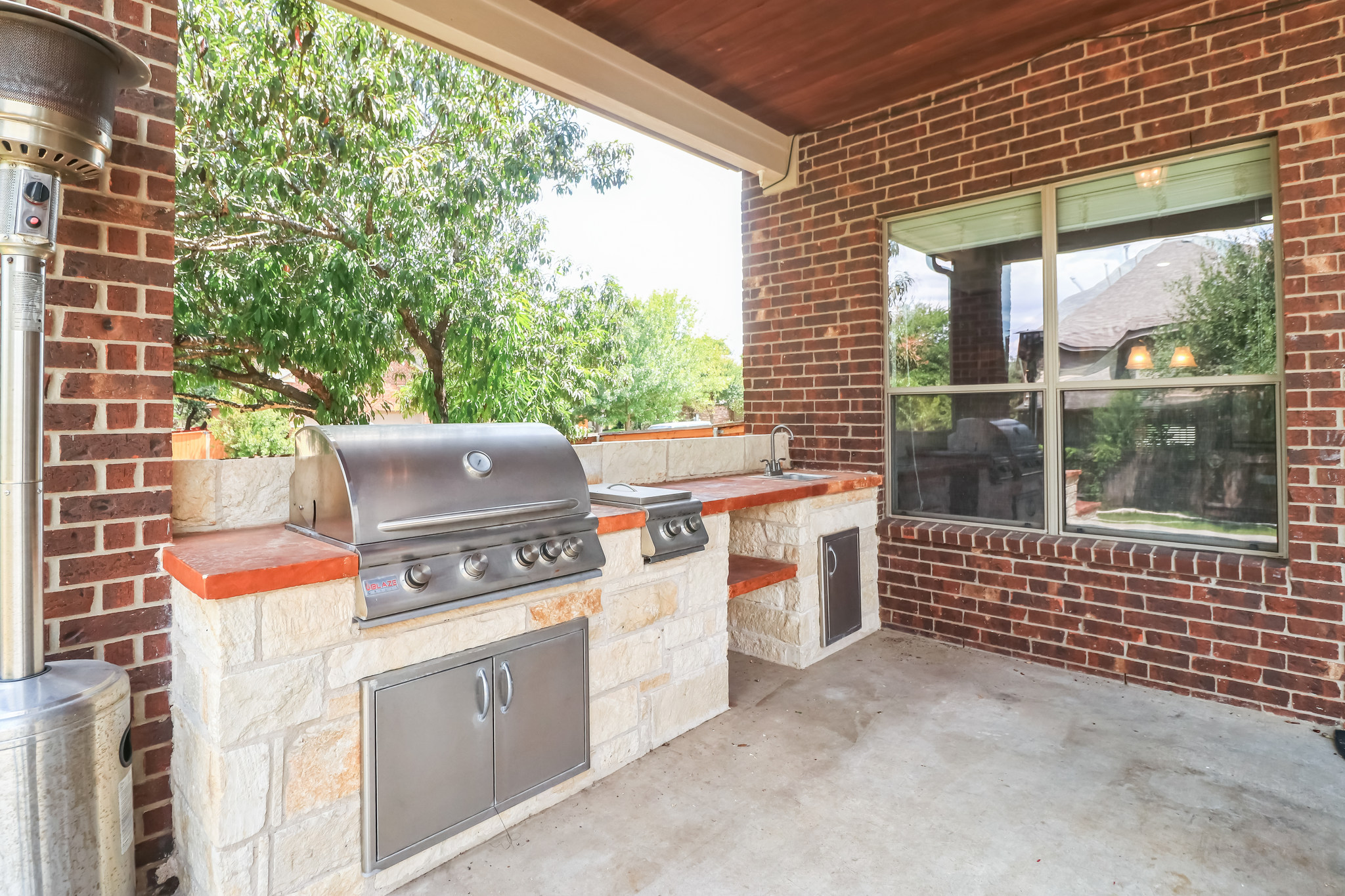 3913 Remington Road Cedar Park, TX 78613 - Photo 13 of 32 An outdoor kitchen features a built-in stone grill station set beneath a covered brick patio.