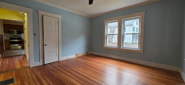 a view of an empty room with wooden floor and a window