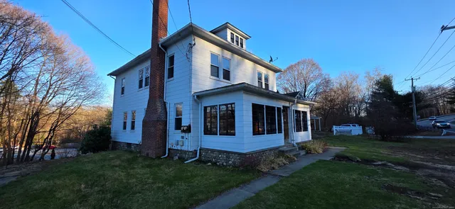 a view of a house with brick walls and a yard with plants