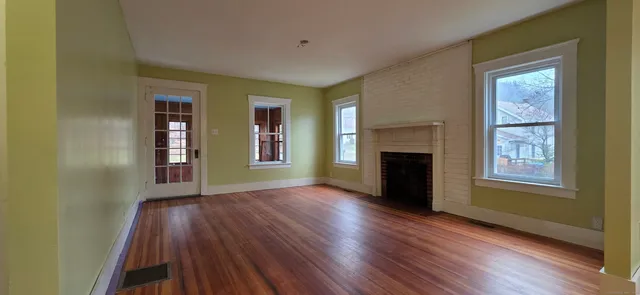 an empty room with windows a fireplace and wooden floor