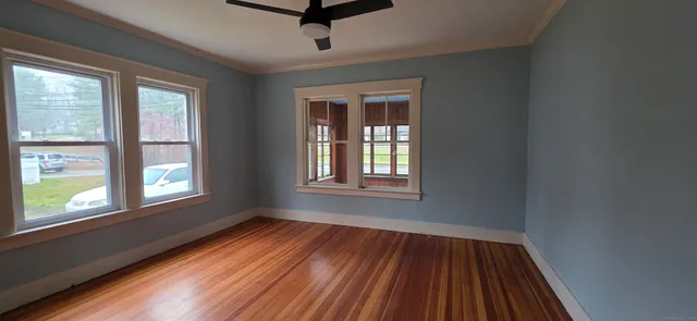 a view of an empty room with wooden floor and a window