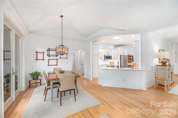 a view of a dining room and livingroom with furniture wooden floor a chandelier