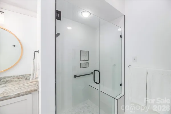 a bathroom with a granite countertop sink a mirror and shower