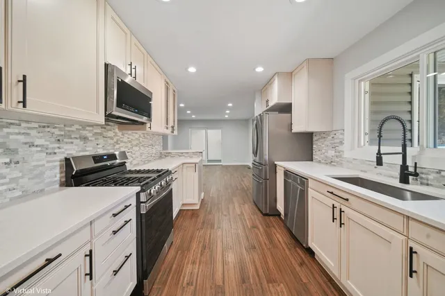a kitchen with stainless steel appliances granite countertop a sink a stove top oven and wooden floors