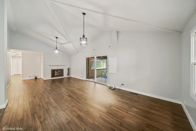 a view of an empty room with wooden floor fireplace and a window