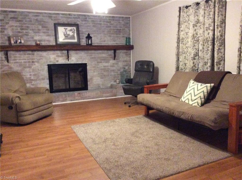 521 Cemetery Street Ronda, NC 28670 - Photo 3 of 13 Living room with white washed brick fireplace, ceiling fan, updated windows, and laminate flooring. Curtains can stay for the new owner.