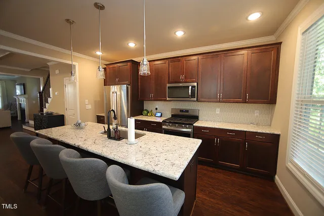 a kitchen with granite countertop kitchen island stainless steel appliances a sink stove and refrigerator