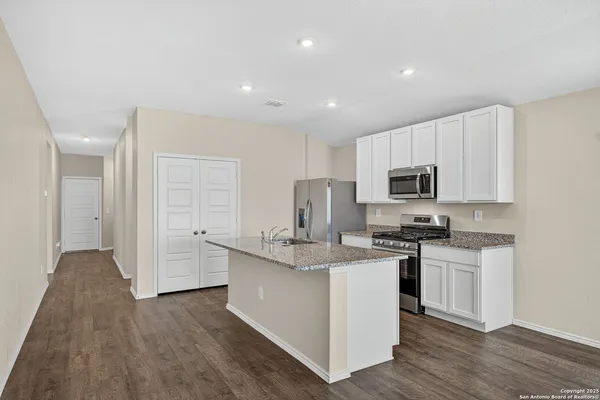 a kitchen with stainless steel appliances granite countertop a stove top oven a sink dishwasher and a refrigerator with wooden floor