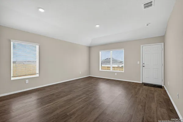 an empty room with wooden floor and windows