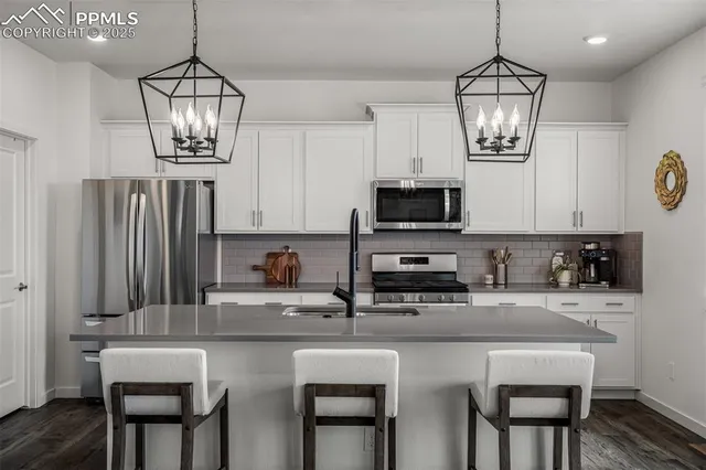a kitchen with stainless steel appliances a chandelier a refrigerator and microwave